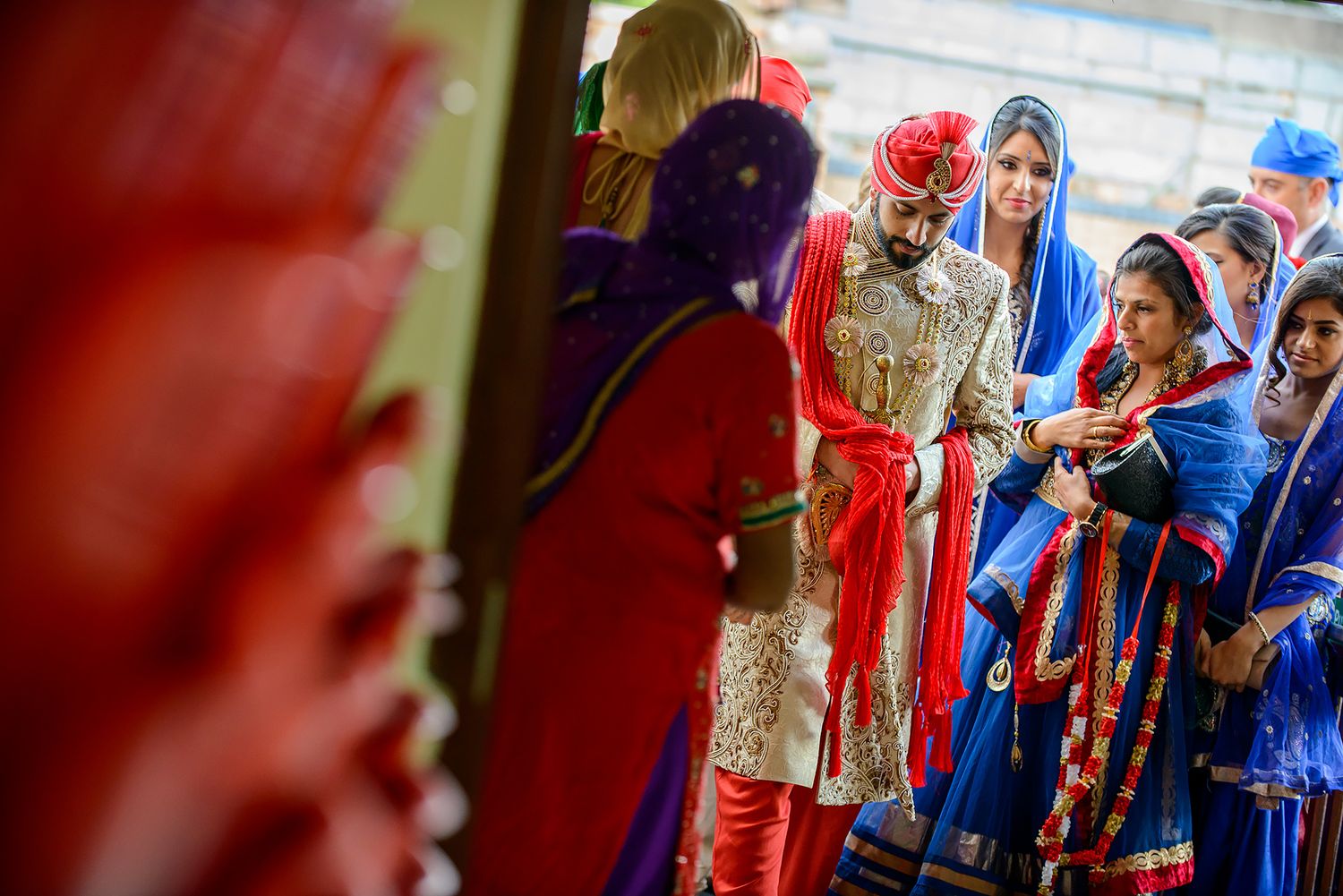 Wedding guests in vibrant blue and red attire gathering during a celebration ceremony.
