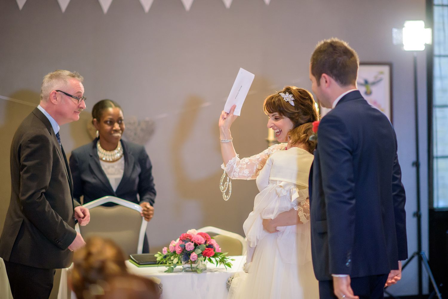 Wedding reception hall with white bunting and guests mingling.