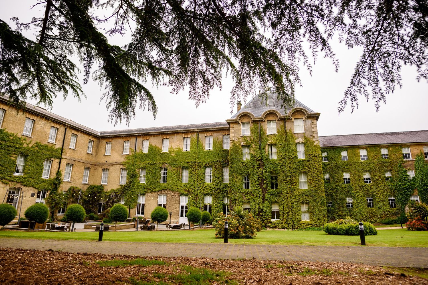 Exterior view of a historic brick building complex with ivy-covered walls and manicured grounds.