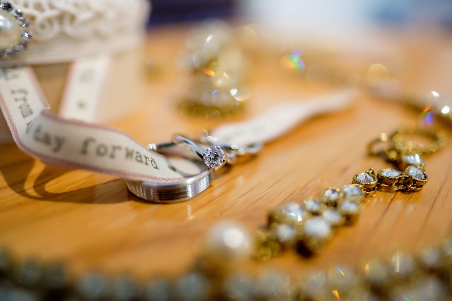 Wedding rings and jewelry details arranged on wooden surface with soft focus.