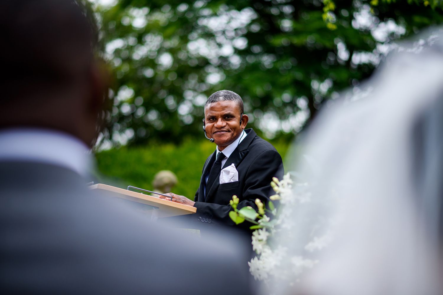 A beautiful outdoor wedding ceremony with guests seated in white chairs on a lush green lawn.
