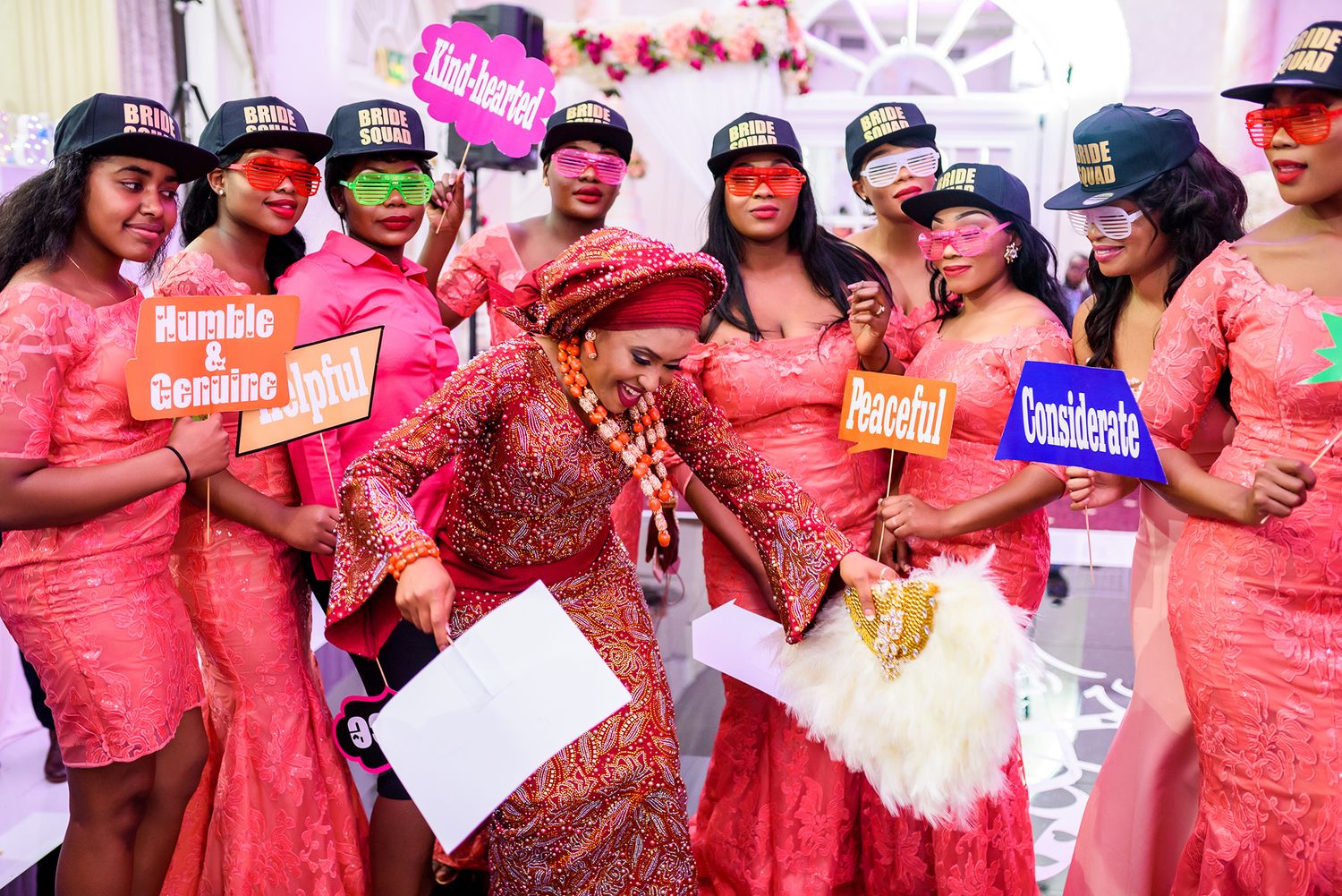 Wedding party members in matching coral dresses dancing and celebrating together.