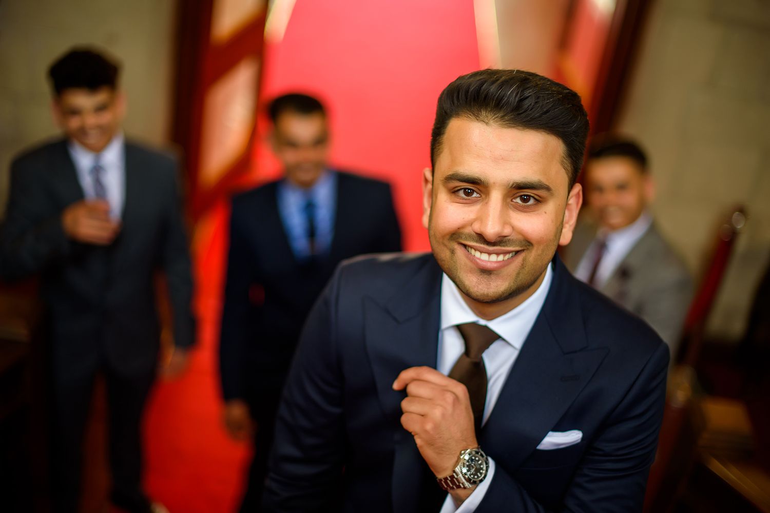 Professional portrait in a formal setting with red wall background.