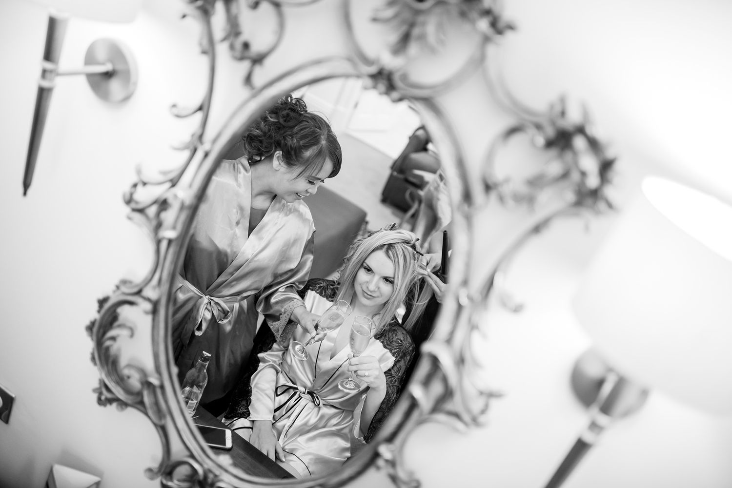 Ornate vintage mirror reflects elegant wedding day preparations in black and white.