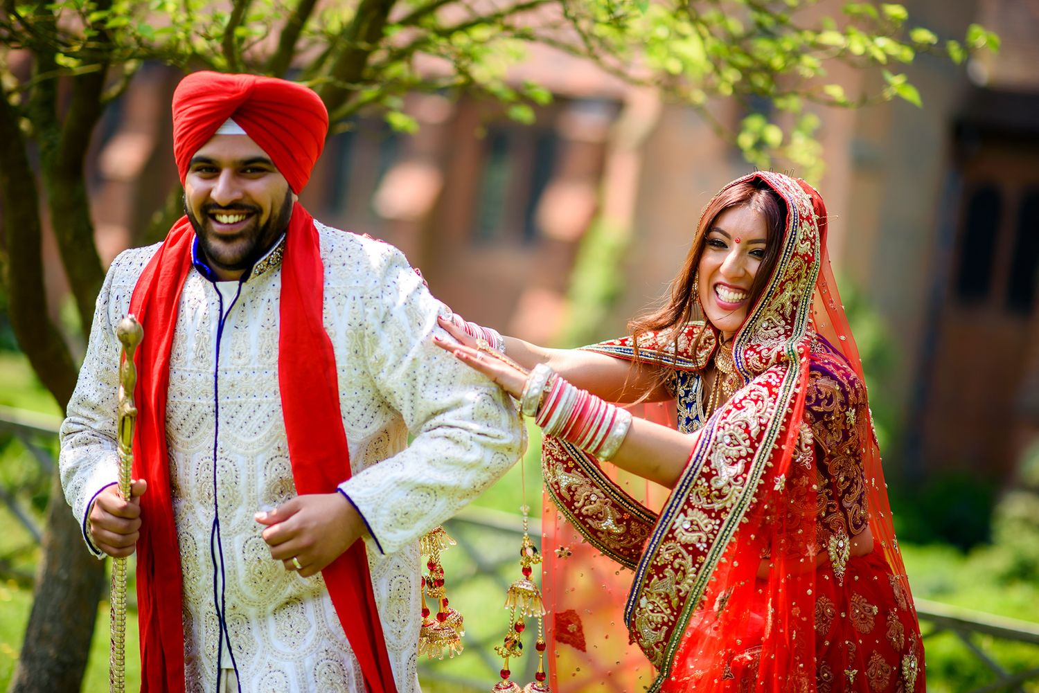 Spring outdoor wedding portraits with traditional Sikh attire and lush greenery.