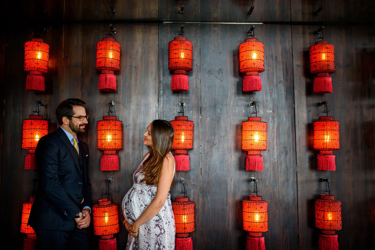 Row of illuminated red paper lanterns creates atmospheric backdrop for romantic scene.