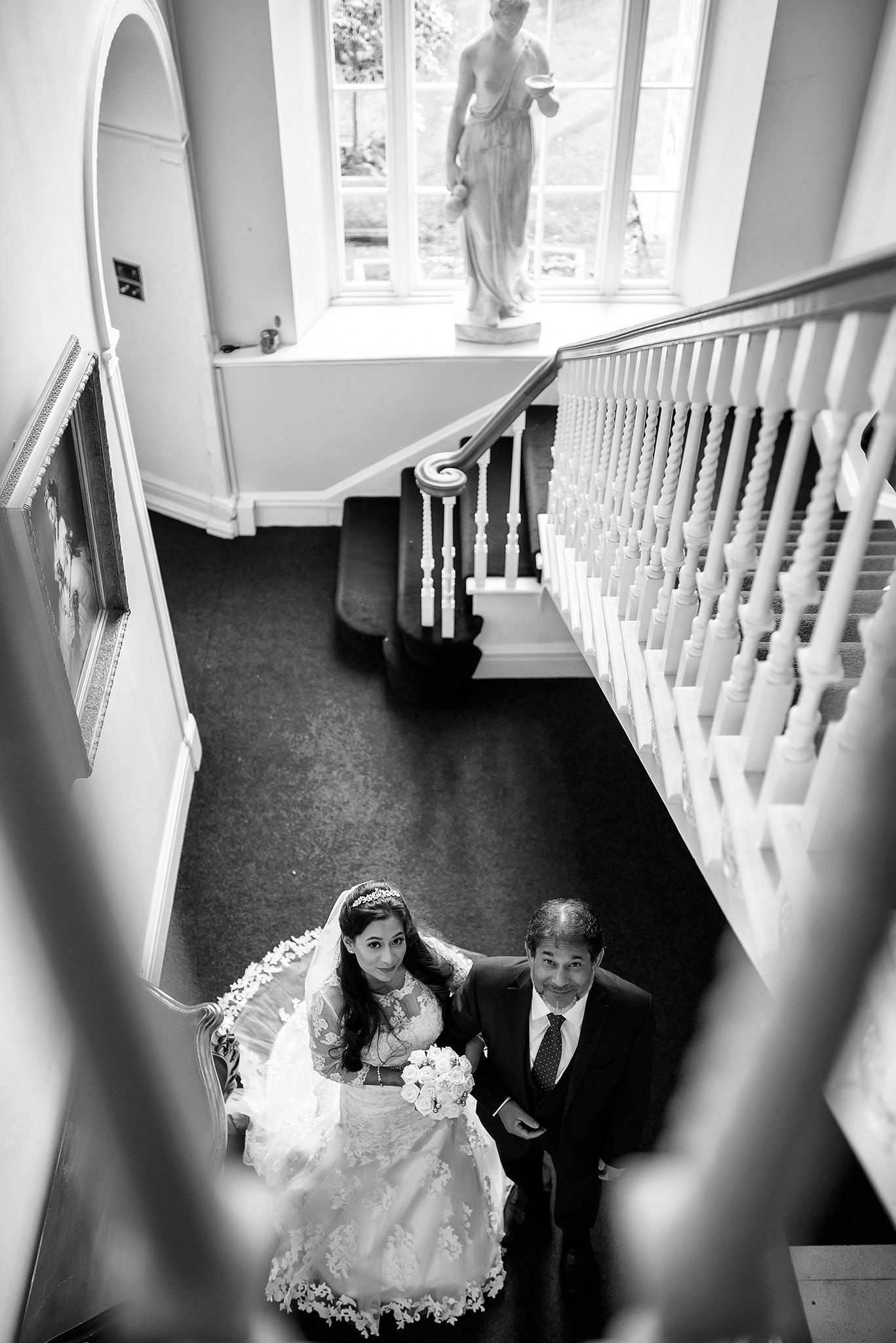 Staircase with white balustrades and carpeted floor seen from an elevated angle.
