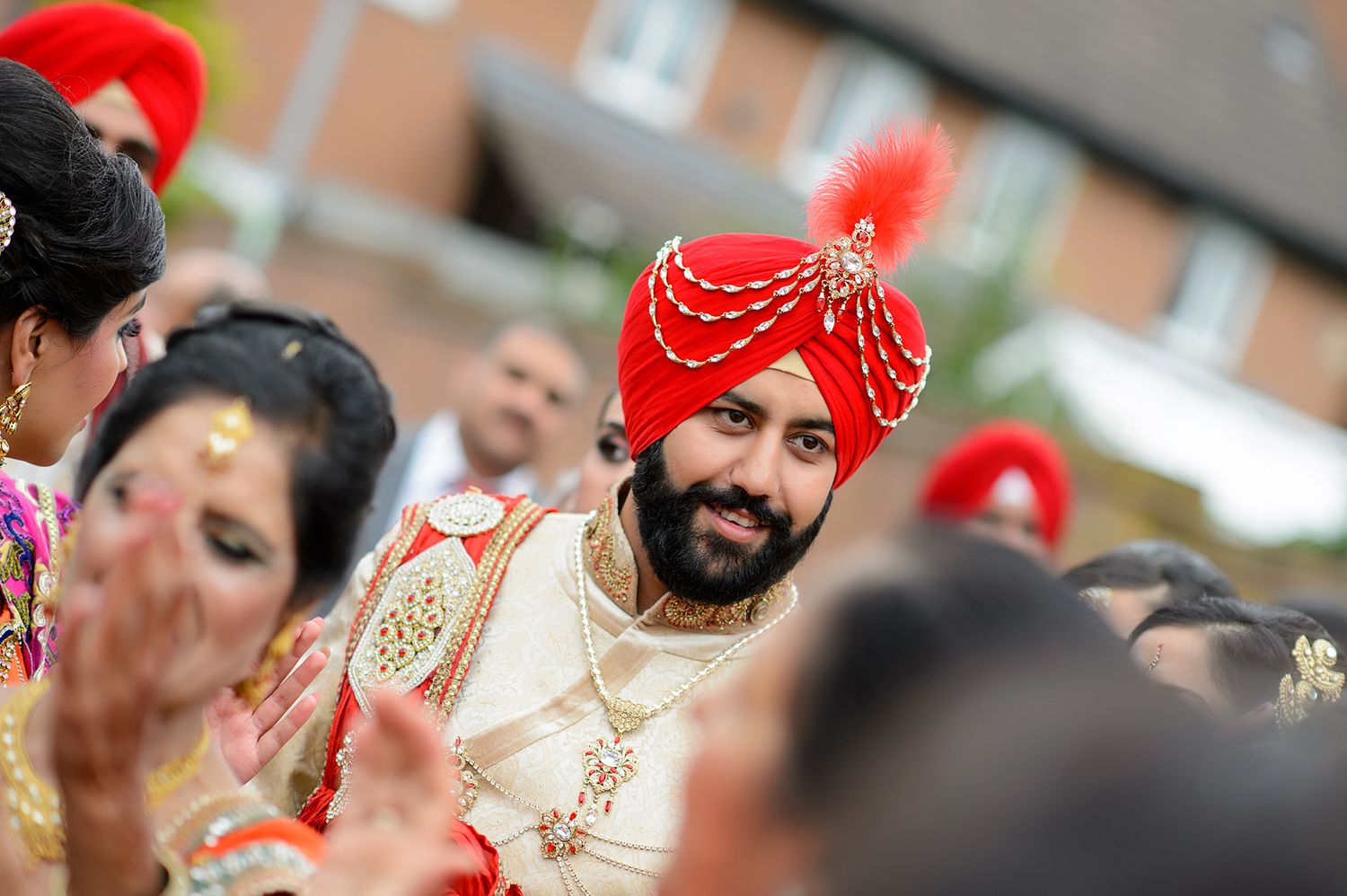 A festive Sikh wedding ceremony with traditional red turban and ornate attire.