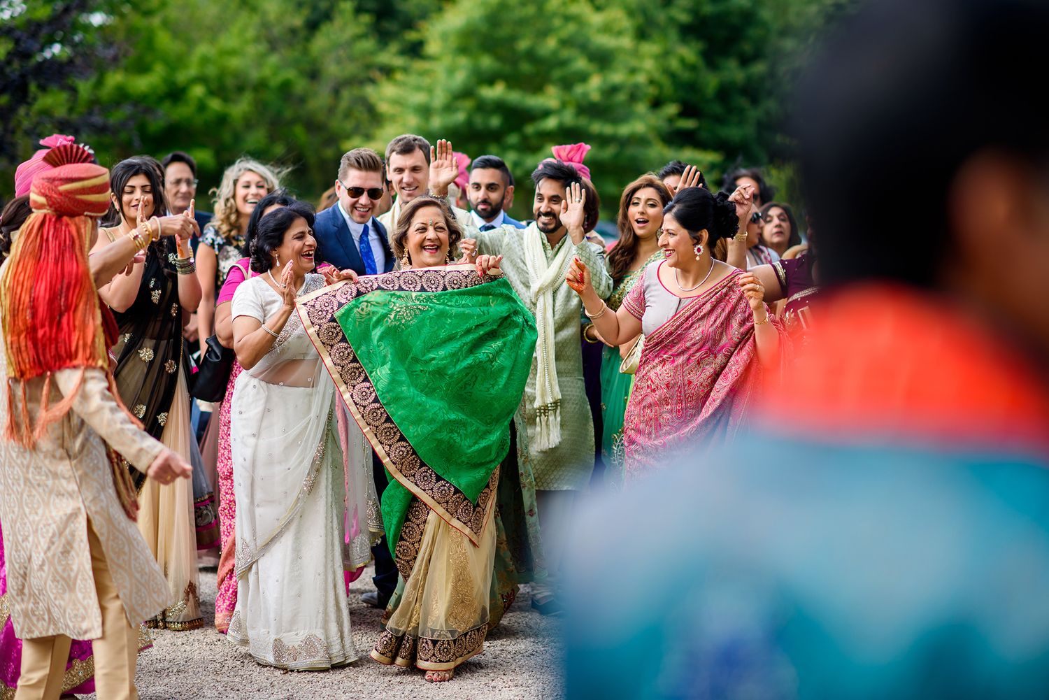 Colorfully dressed wedding guests celebrating outdoors in joyful procession.