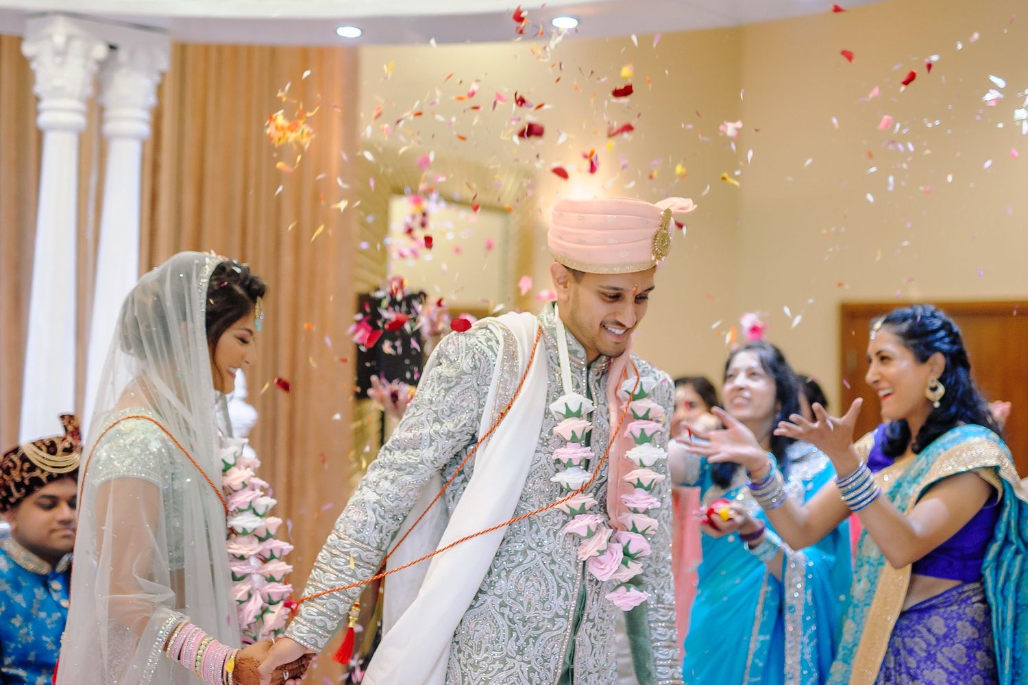 Wedding celebration with rose petals falling during an indoor ceremony.