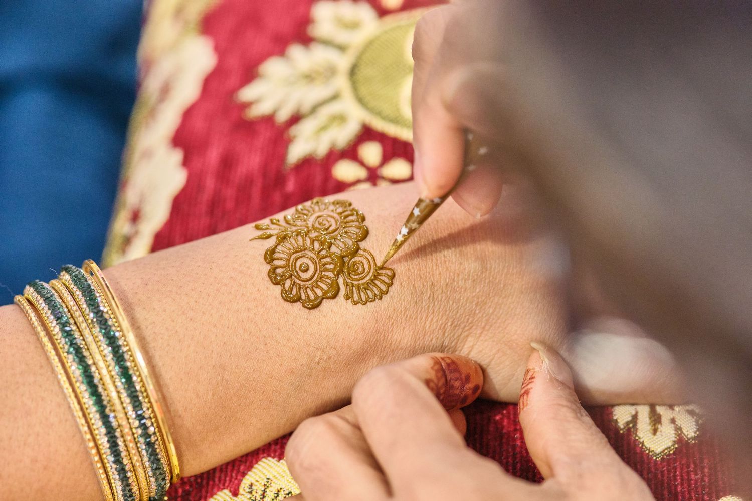 Hands adorned with henna designs and bangles during a traditional Indian wedding ceremony.