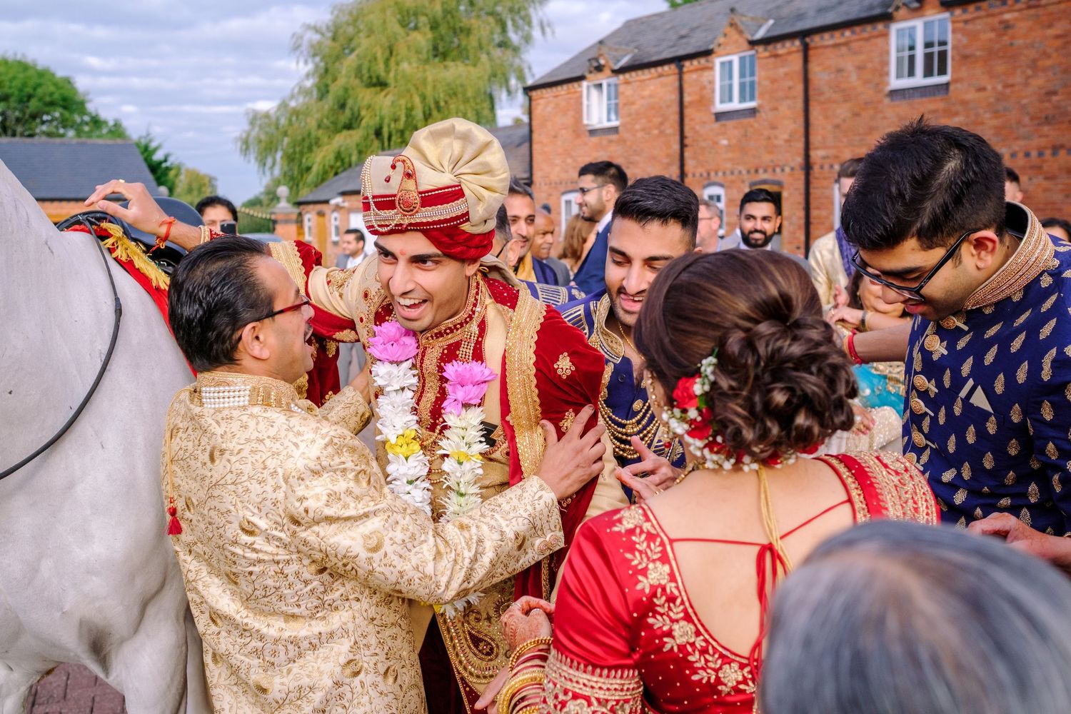 Joyful wedding guests celebrate during a traditional Indian ceremony with vibrant red and gold attire.