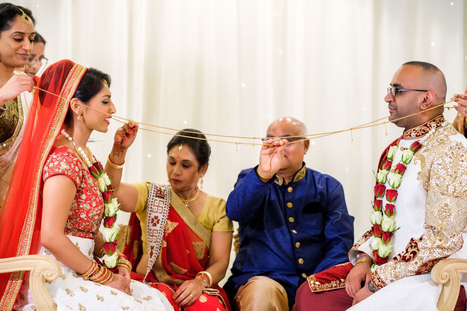 Guests participate in a traditional Indian wedding ceremony with vibrant red and gold decor.