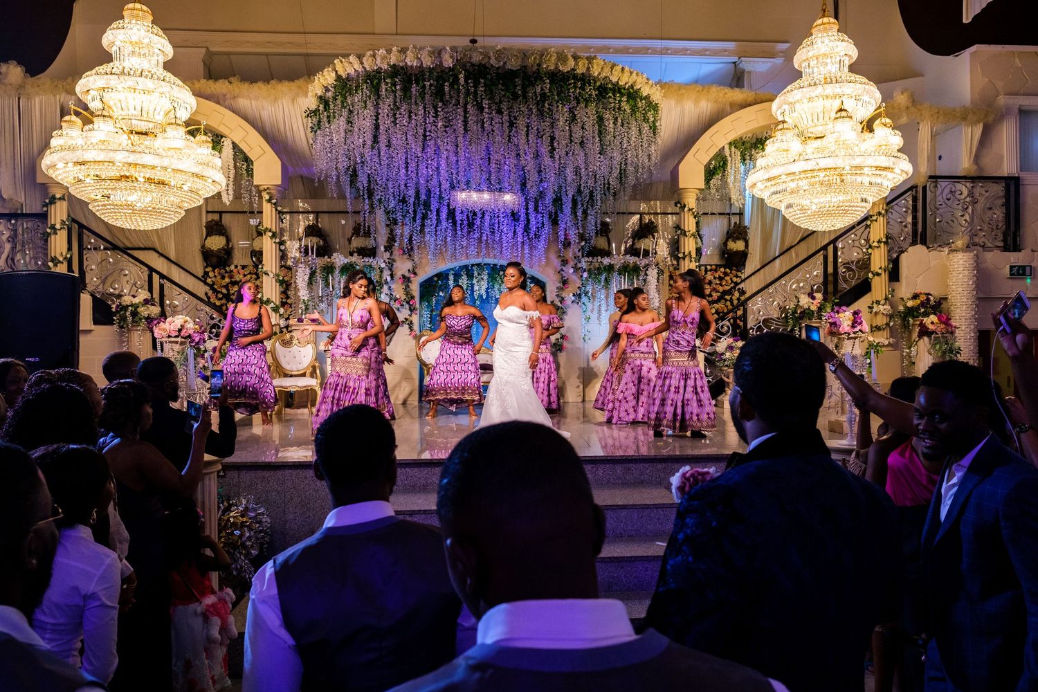 Wedding reception performance on stage with crystal chandeliers and purple lighting.