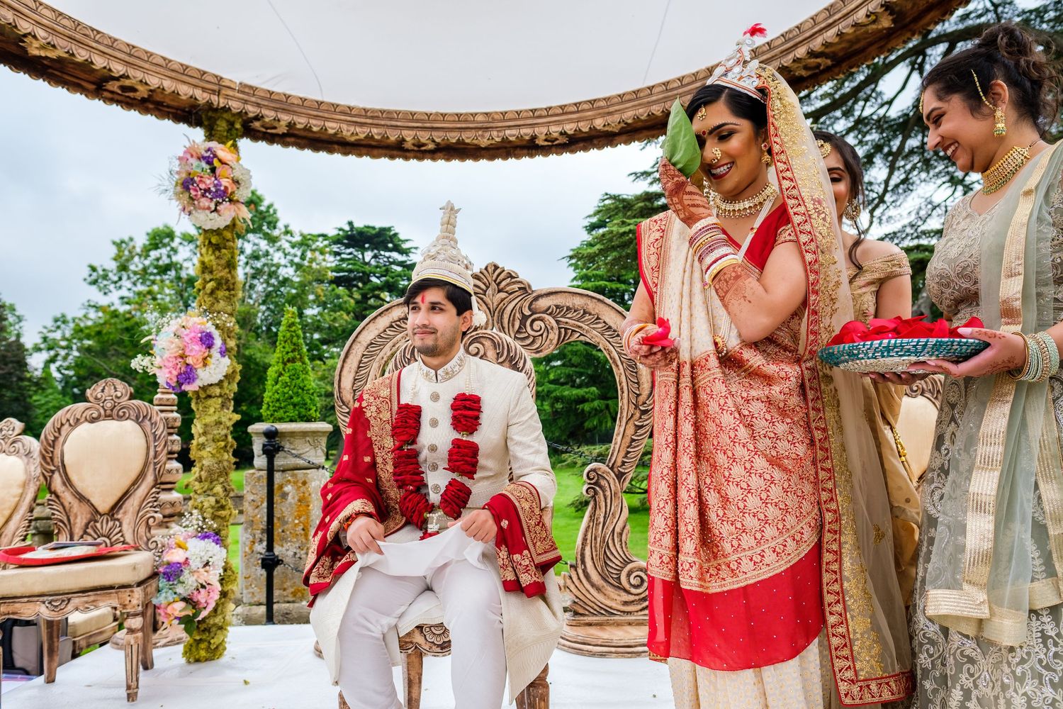 Colorful traditional Indian wedding ceremony with ornate decorations and attire in an outdoor garden setting.