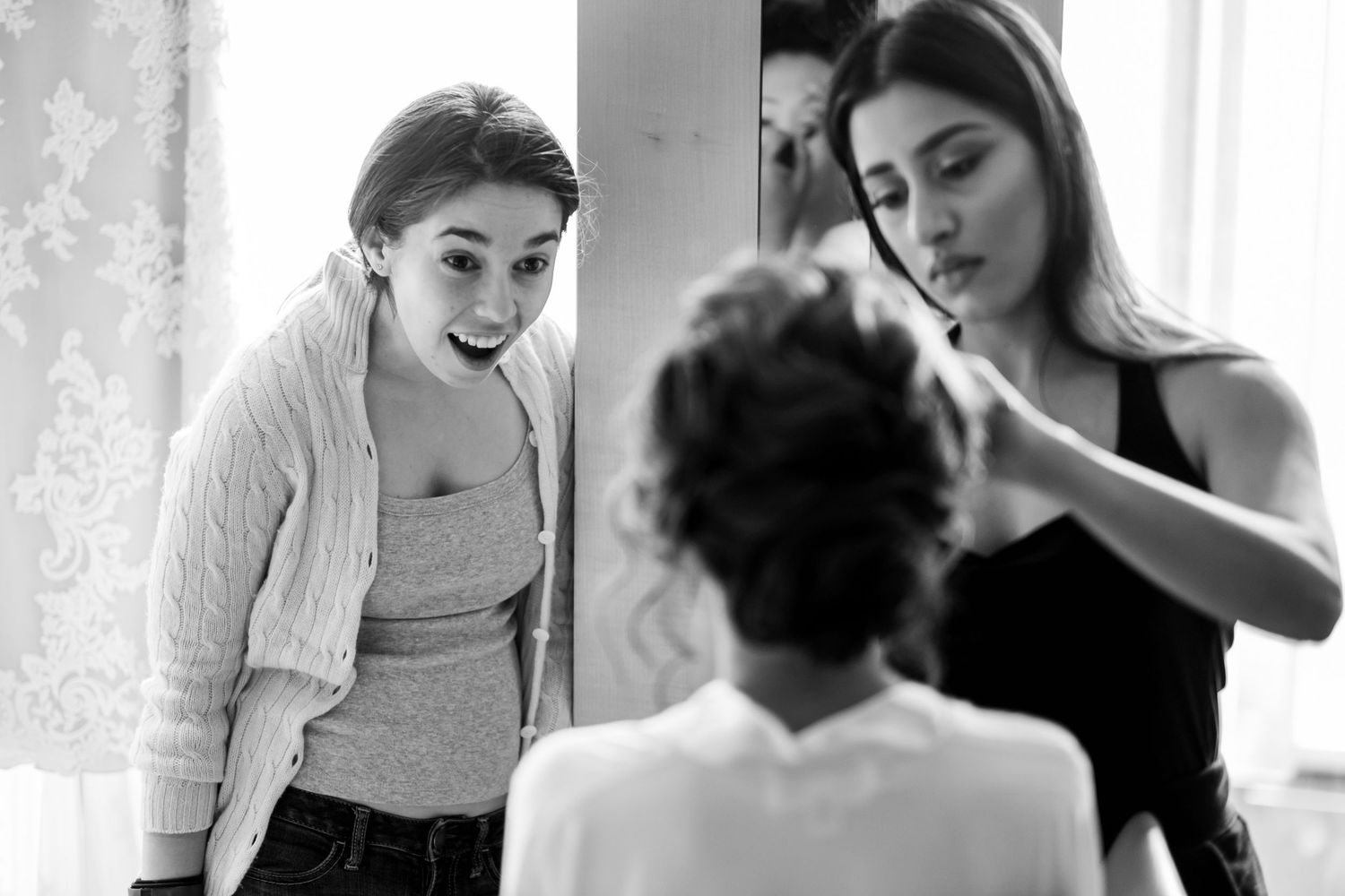Two stylists work together on a client's hair in a bright salon setting.