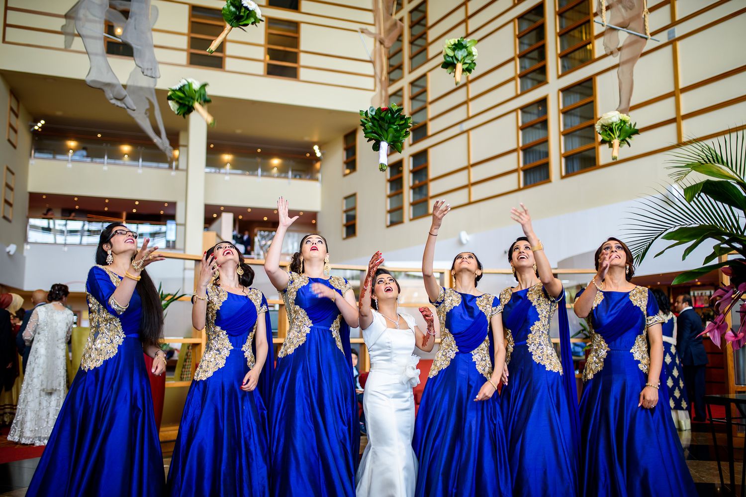 Bridesmaids in vibrant blue dresses posing with bride in elegant indoor setting.