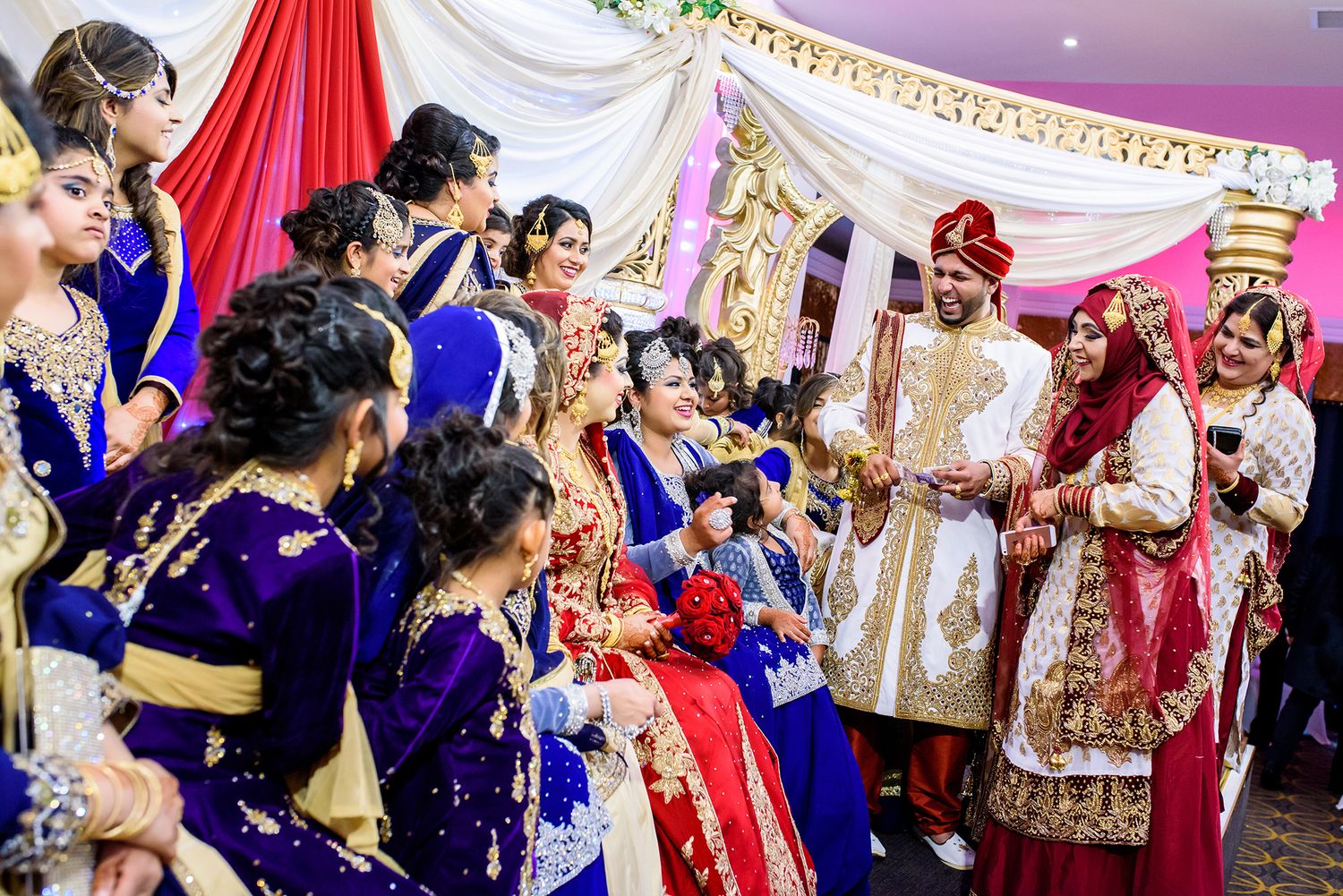 Celebration at an Indian wedding venue with red and white decorative draping and festive atmosphere.