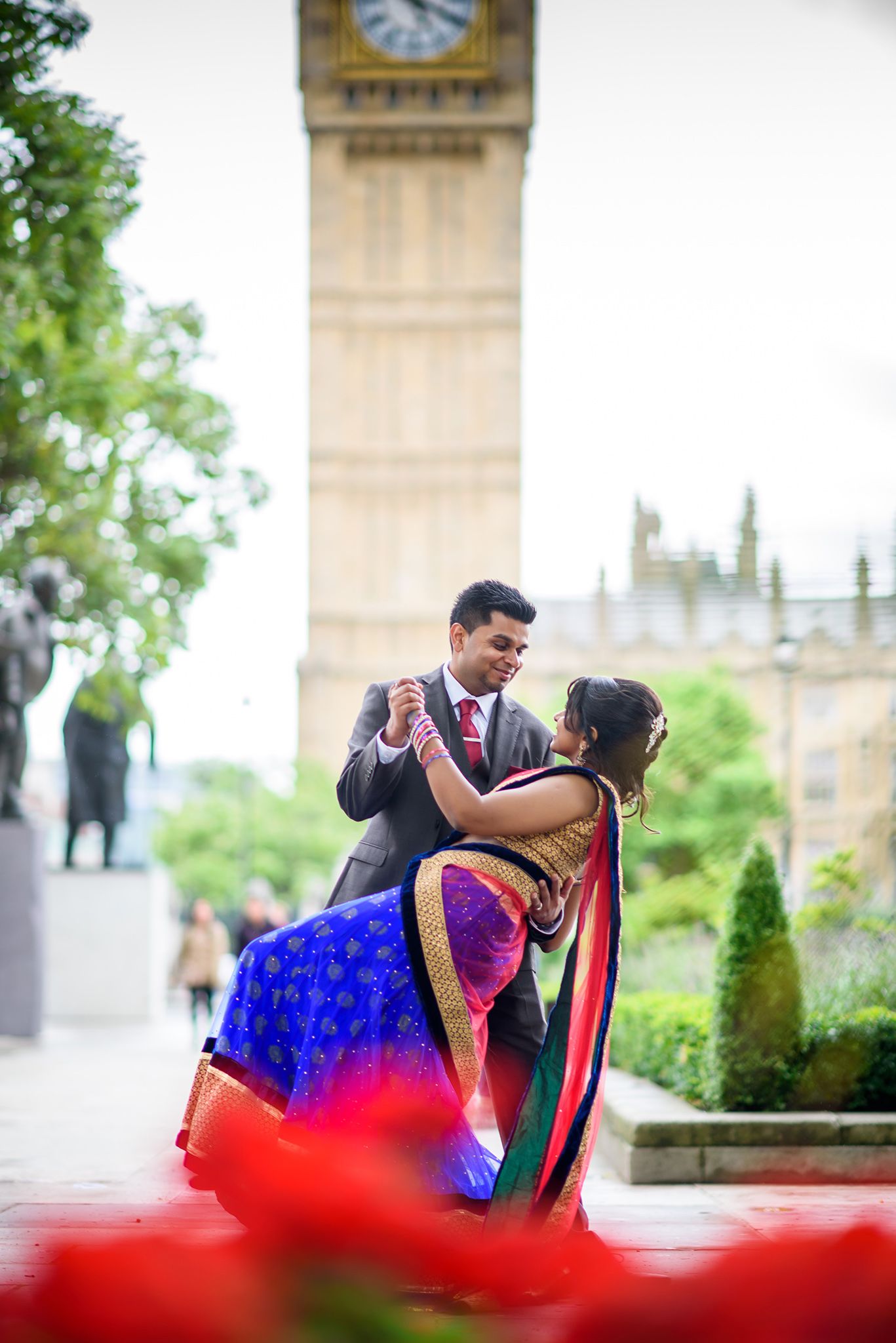 Couple dancing romantically near pillars with a vibrant red dress flowing in motion.