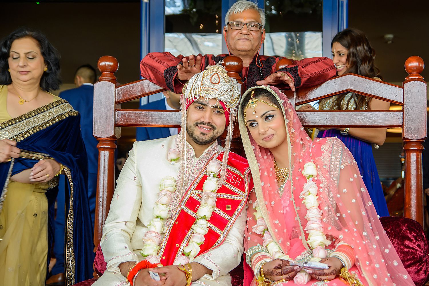 Traditional Indian marriage ceremony with bride in pink lehenga and groom in ivory attire.