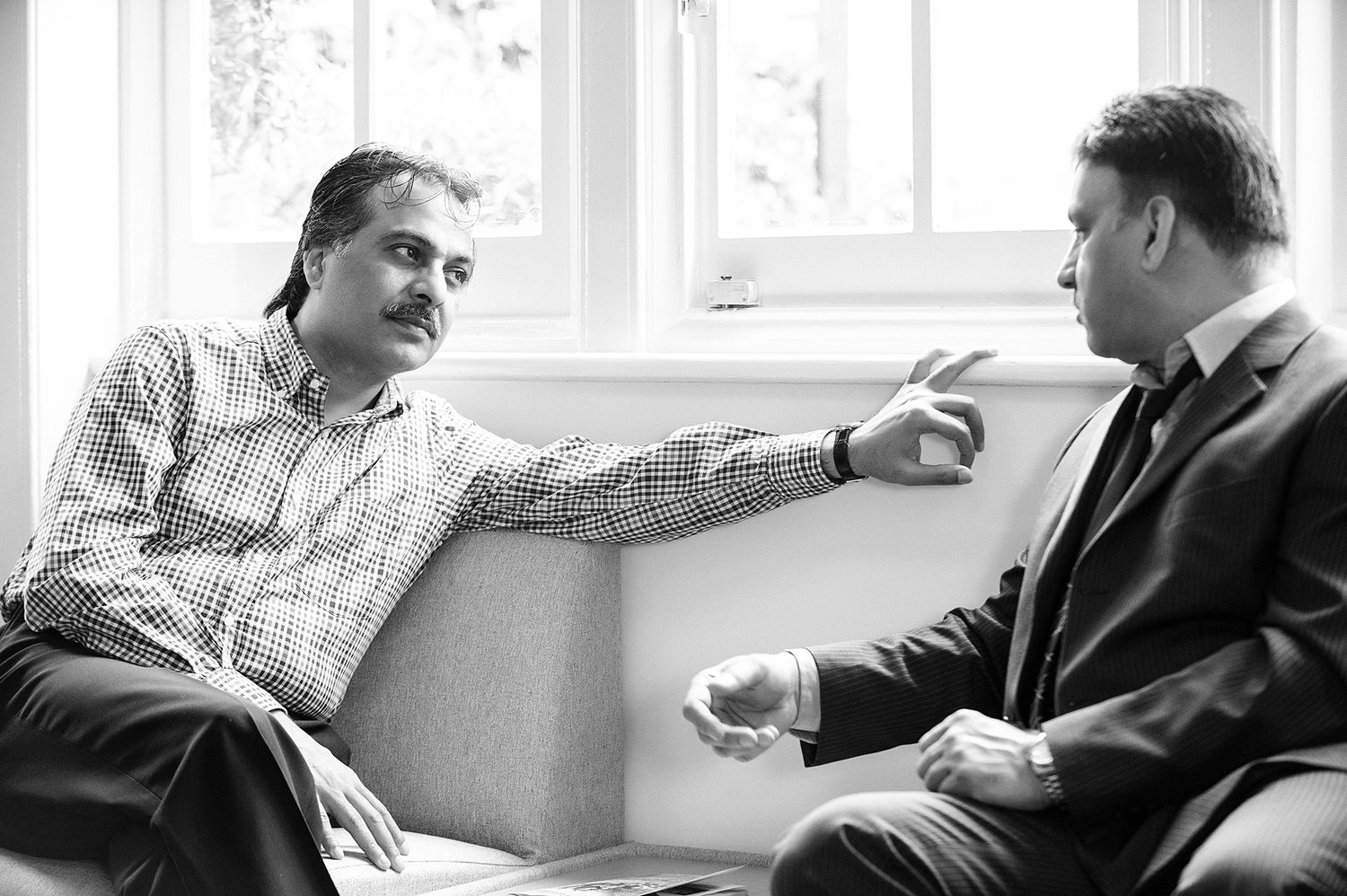 People seated in a bright room with windows having an intimate conversation.