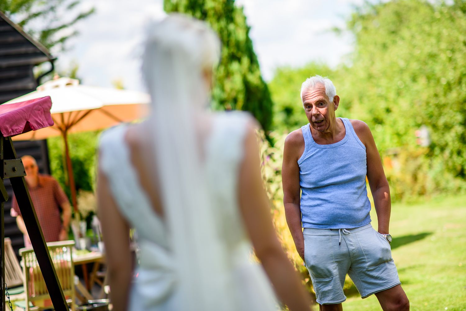 Guests mingling at an outdoor garden wedding reception on a bright summer day.