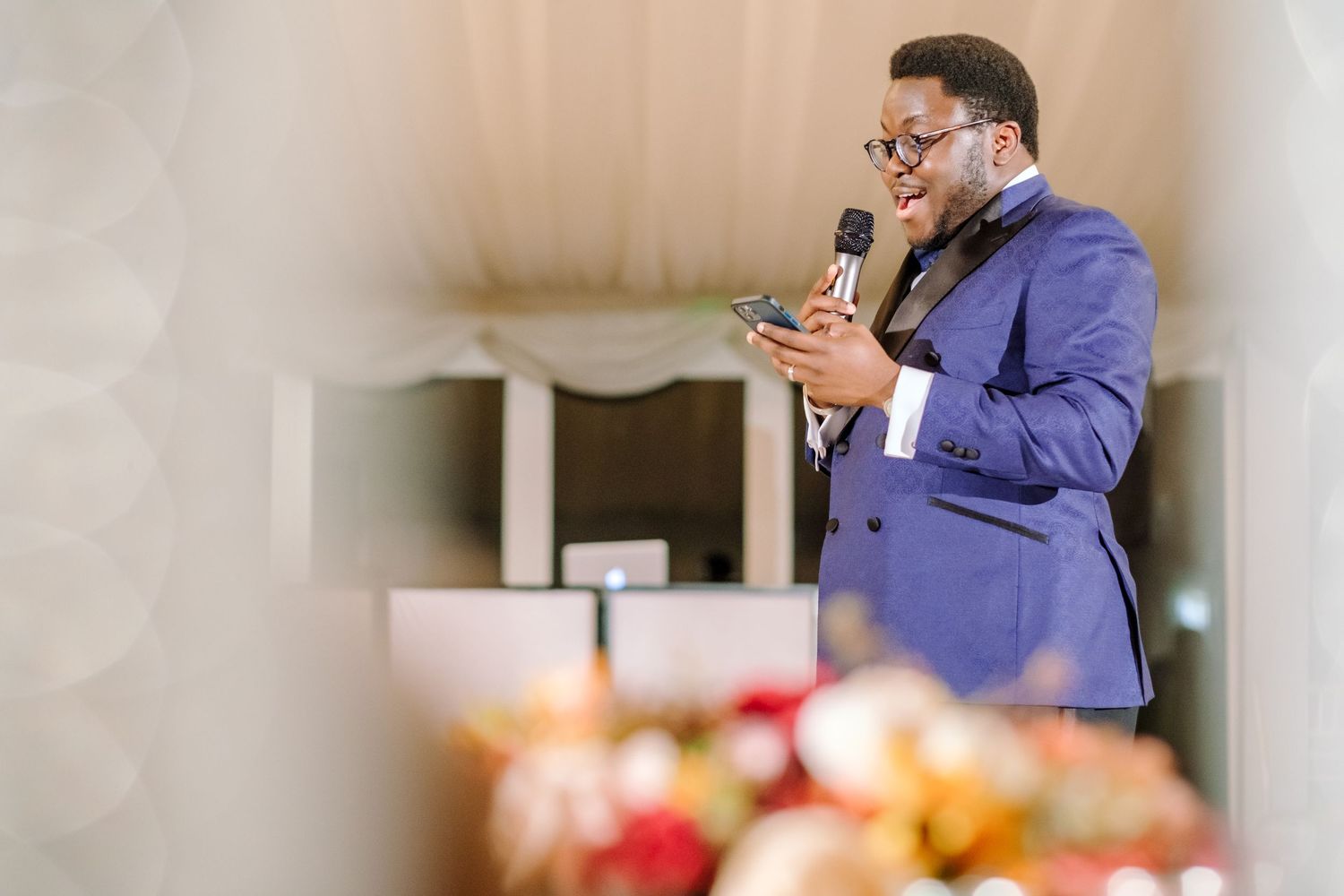 Guests in formal attire enjoying speeches and toasts during an indoor wedding reception.