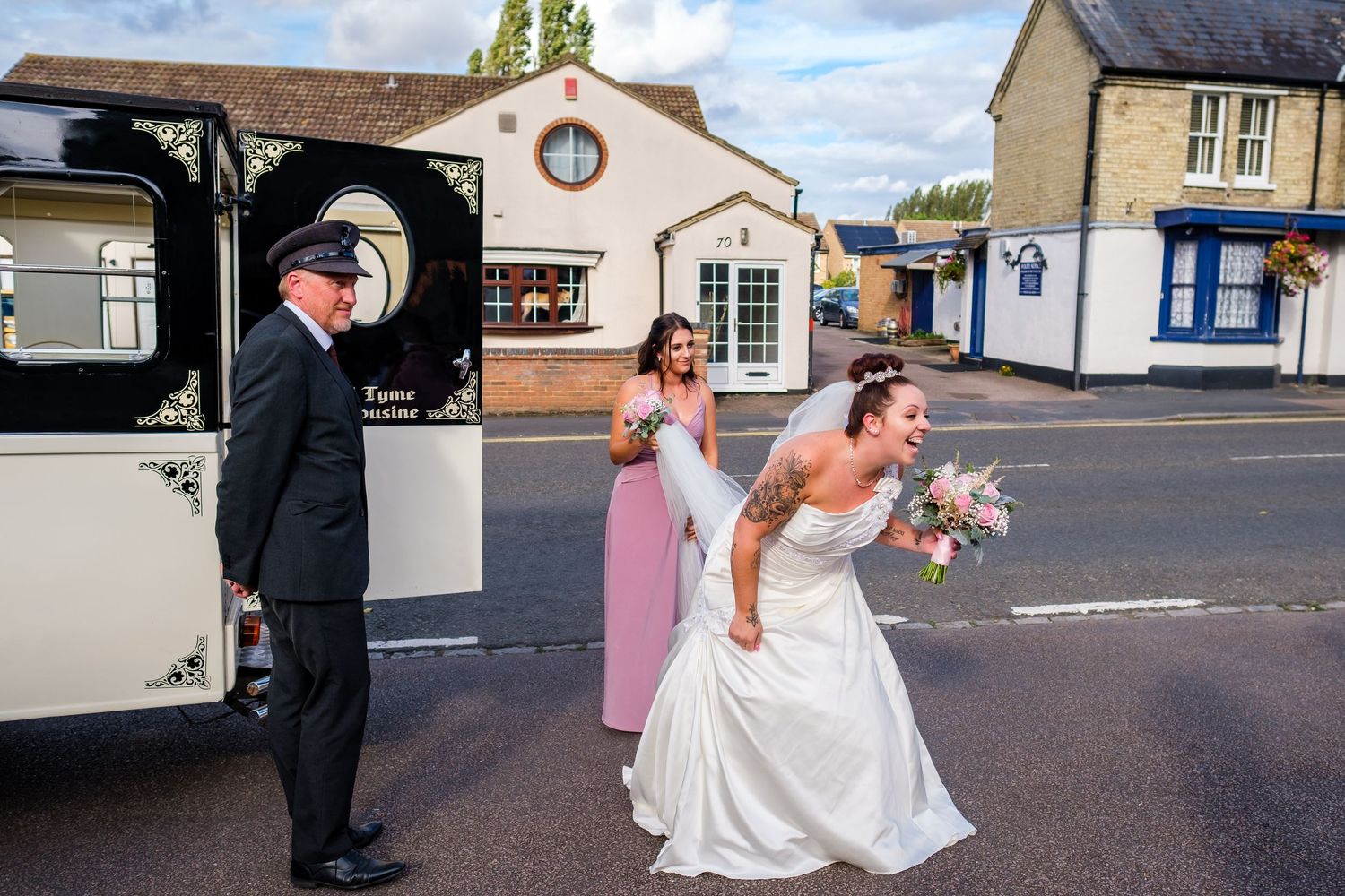Wedding party members walking and posing outside a brick building on a sunny day.