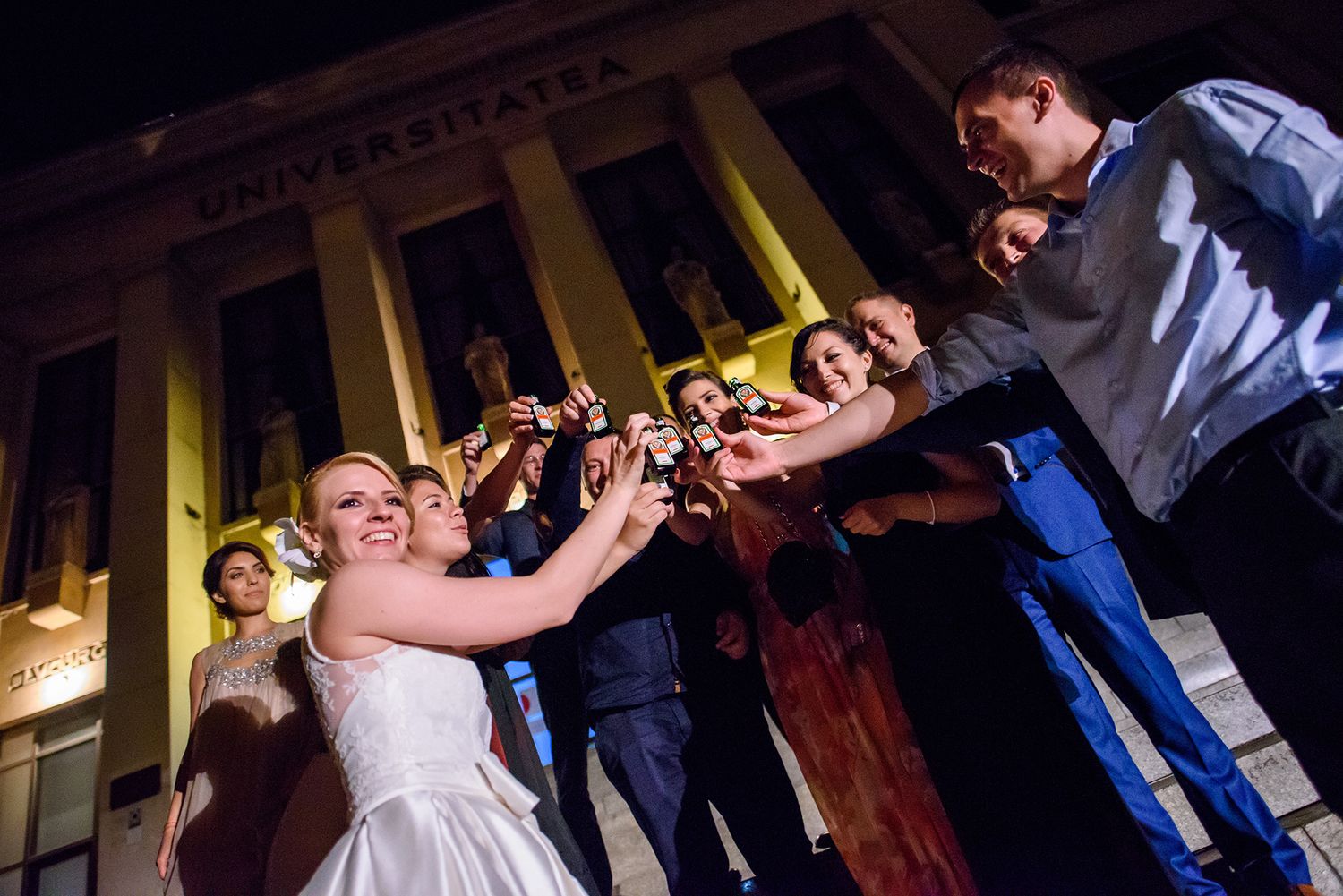 Couples dancing together during an evening wedding celebration with dramatic lighting.