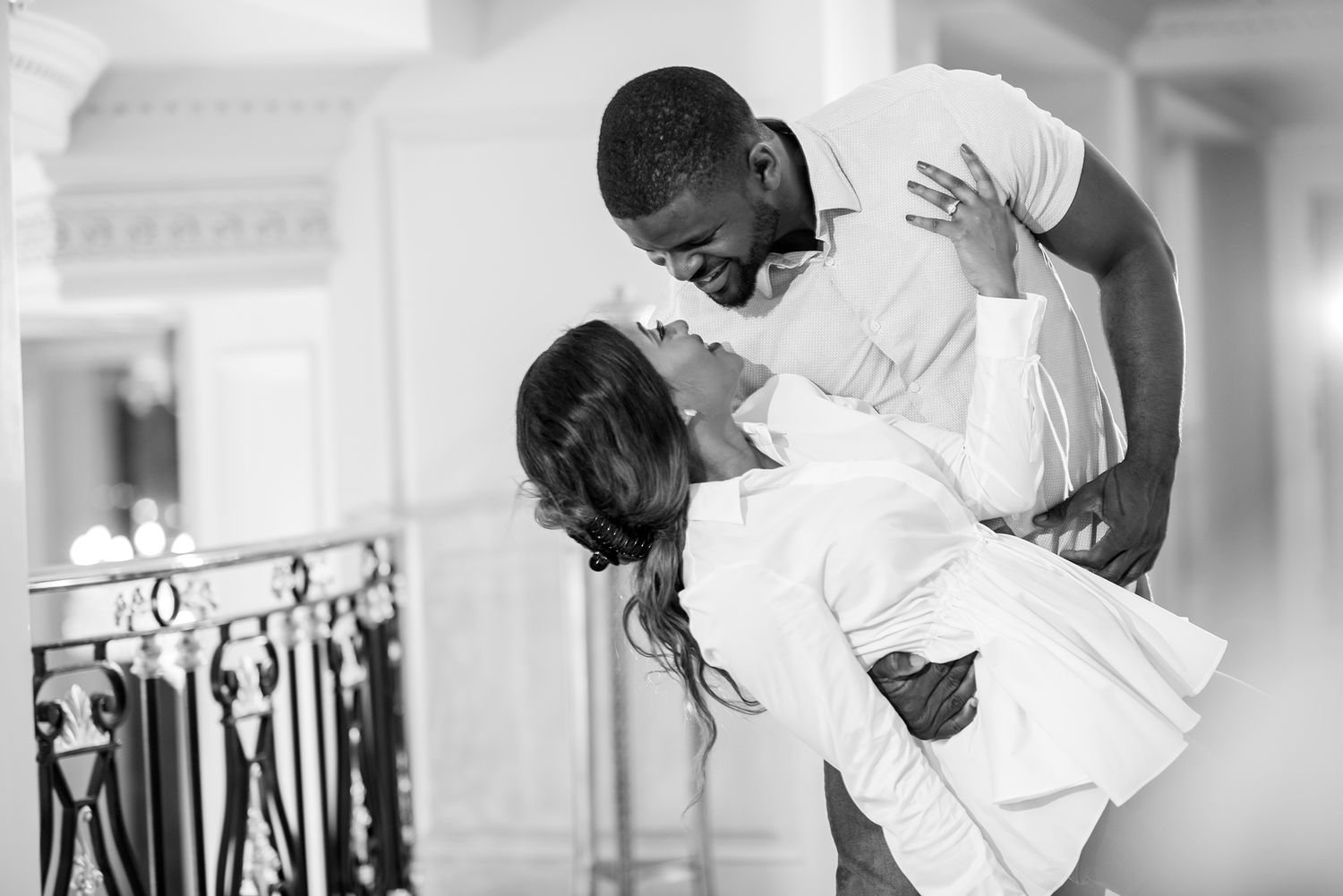 A playful couple shares laughs and embraces in a bright indoor setting with modern decor.