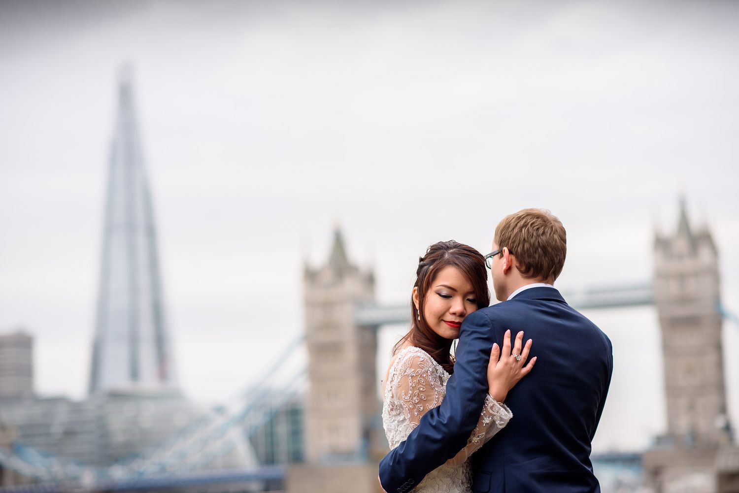 A romantic wedding portrait with London's iconic Tower Bridge and skyline in the background.