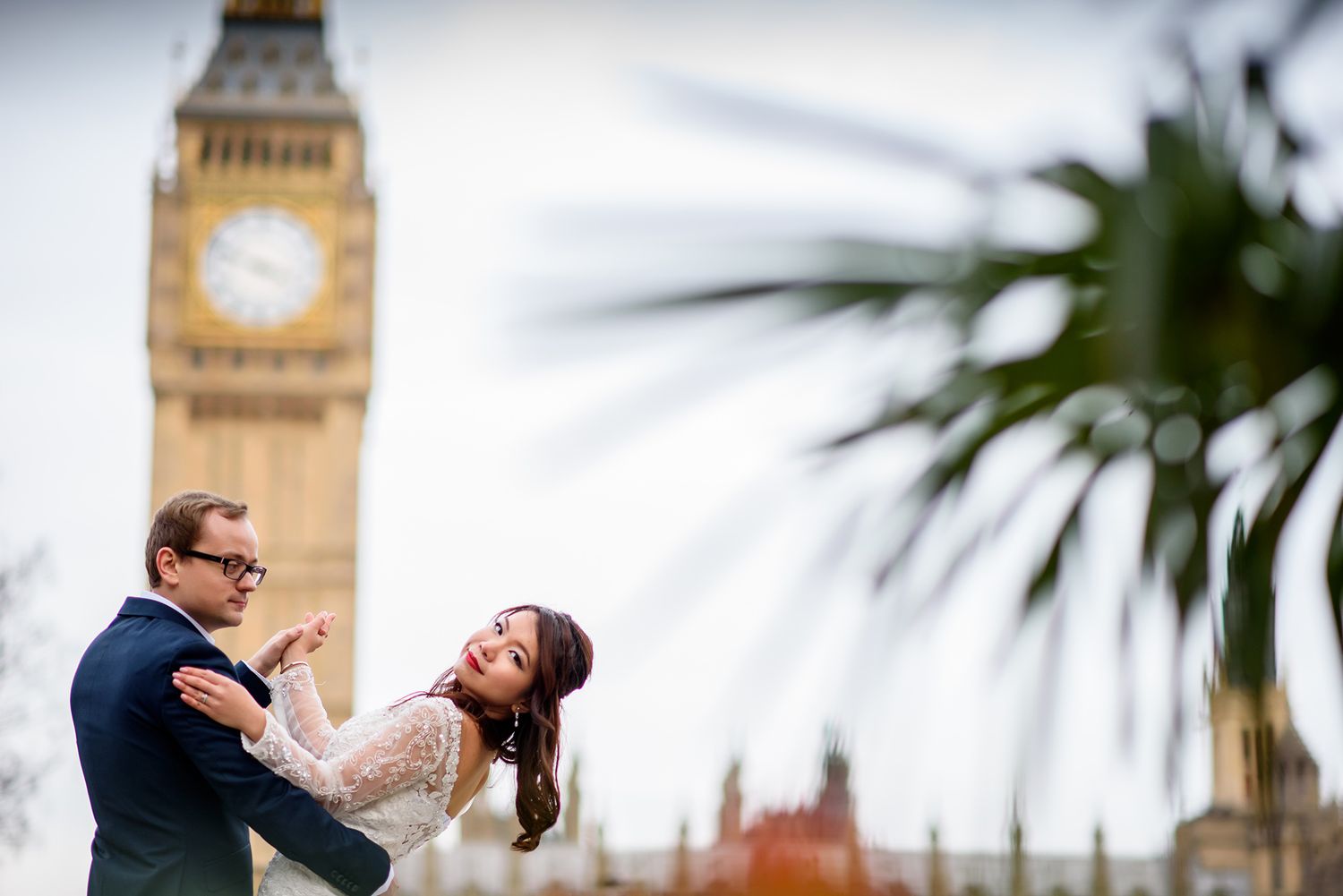 Romantic wedding portrait in front of Big Ben with palm trees framing the scene.