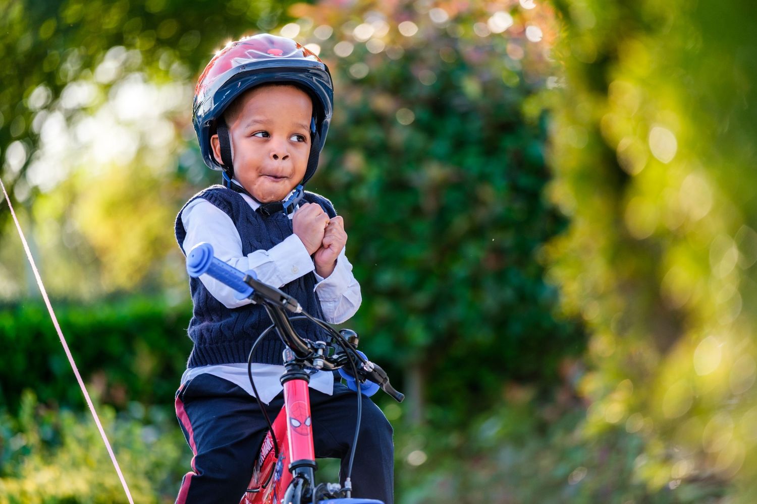 Child in blue helmet and sports gear pauses during outdoor activity.