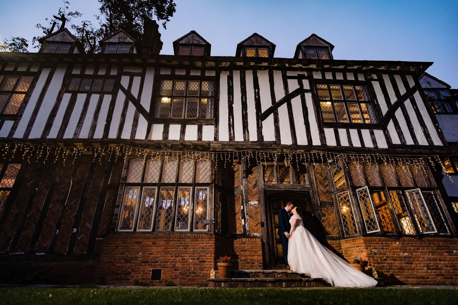 Tudor-style manor house wedding venue against blue sky with dramatic architectural details.