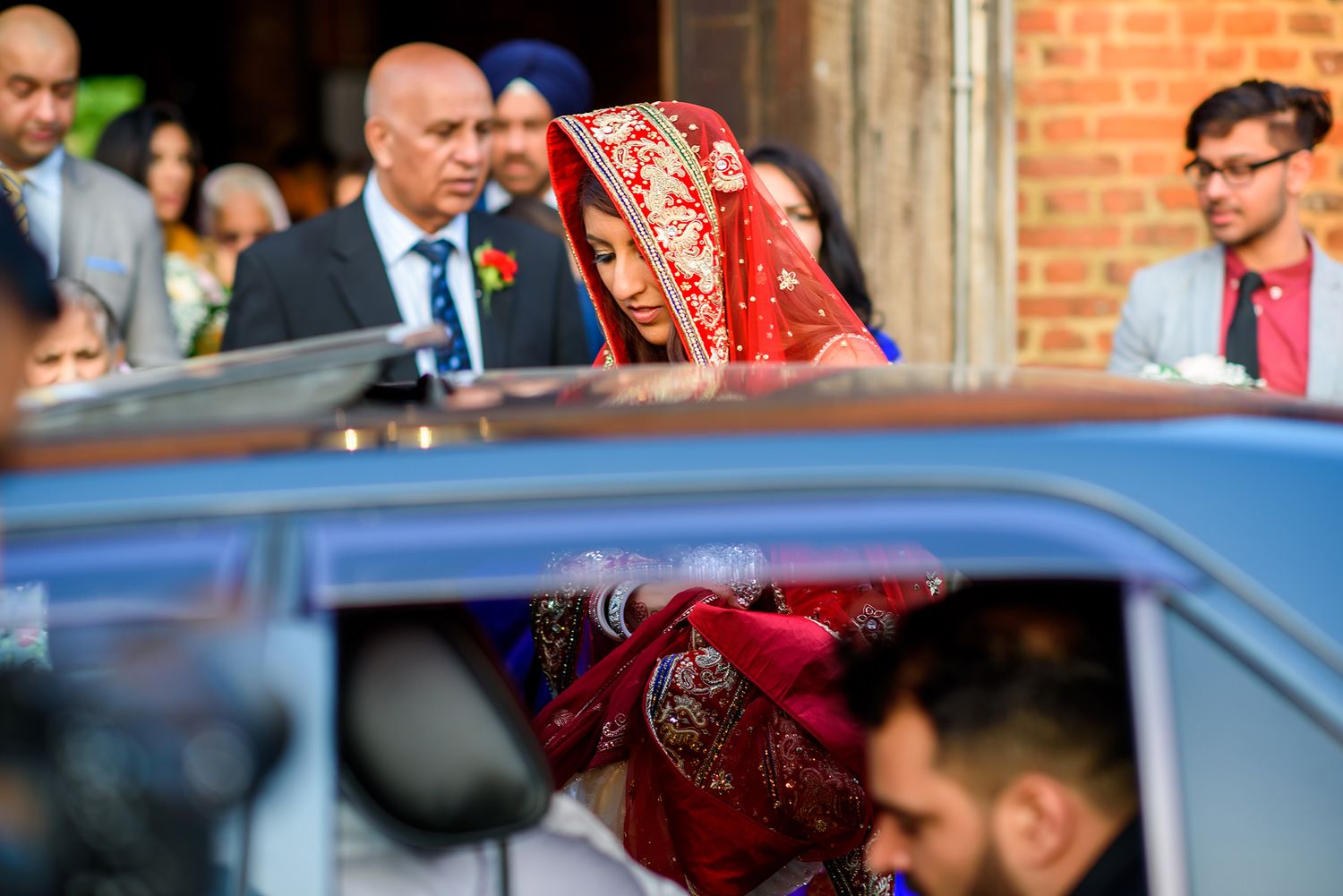 Wedding celebration featuring traditional cultural attire and decor against brick backdrop.