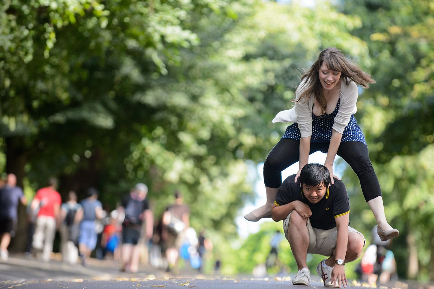 Couple playing and running through a lush green park pathway.