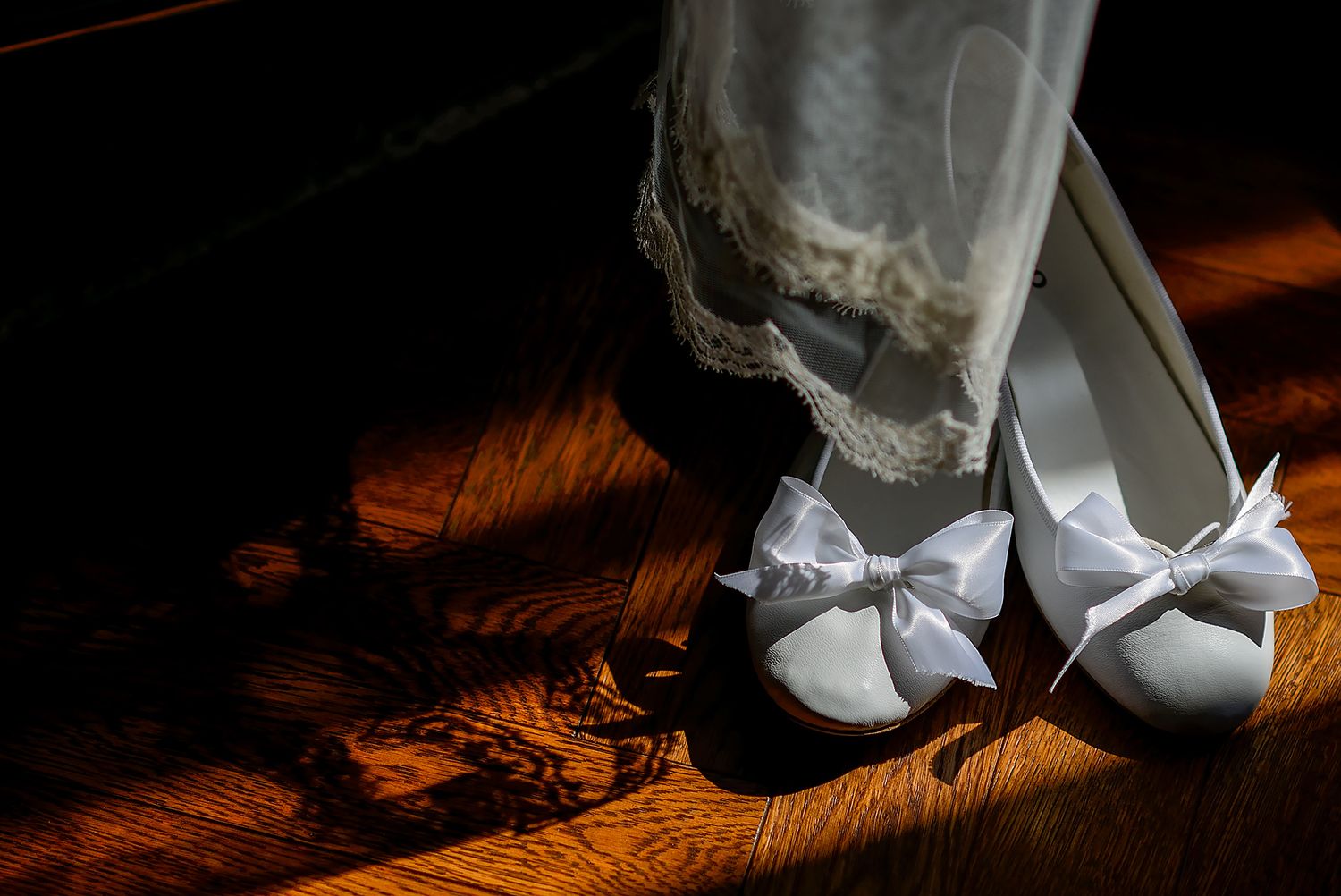 Close-up detail shots of bridal shoes and dress hem on wooden flooring.