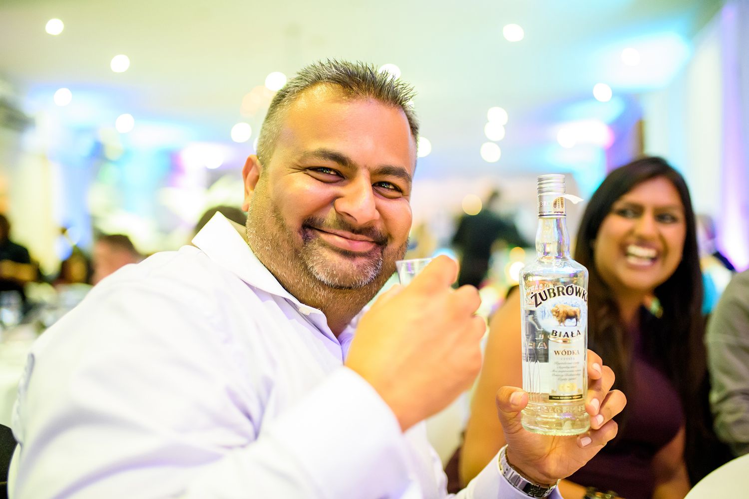 Guest raises a bottle in celebration during the wedding reception.