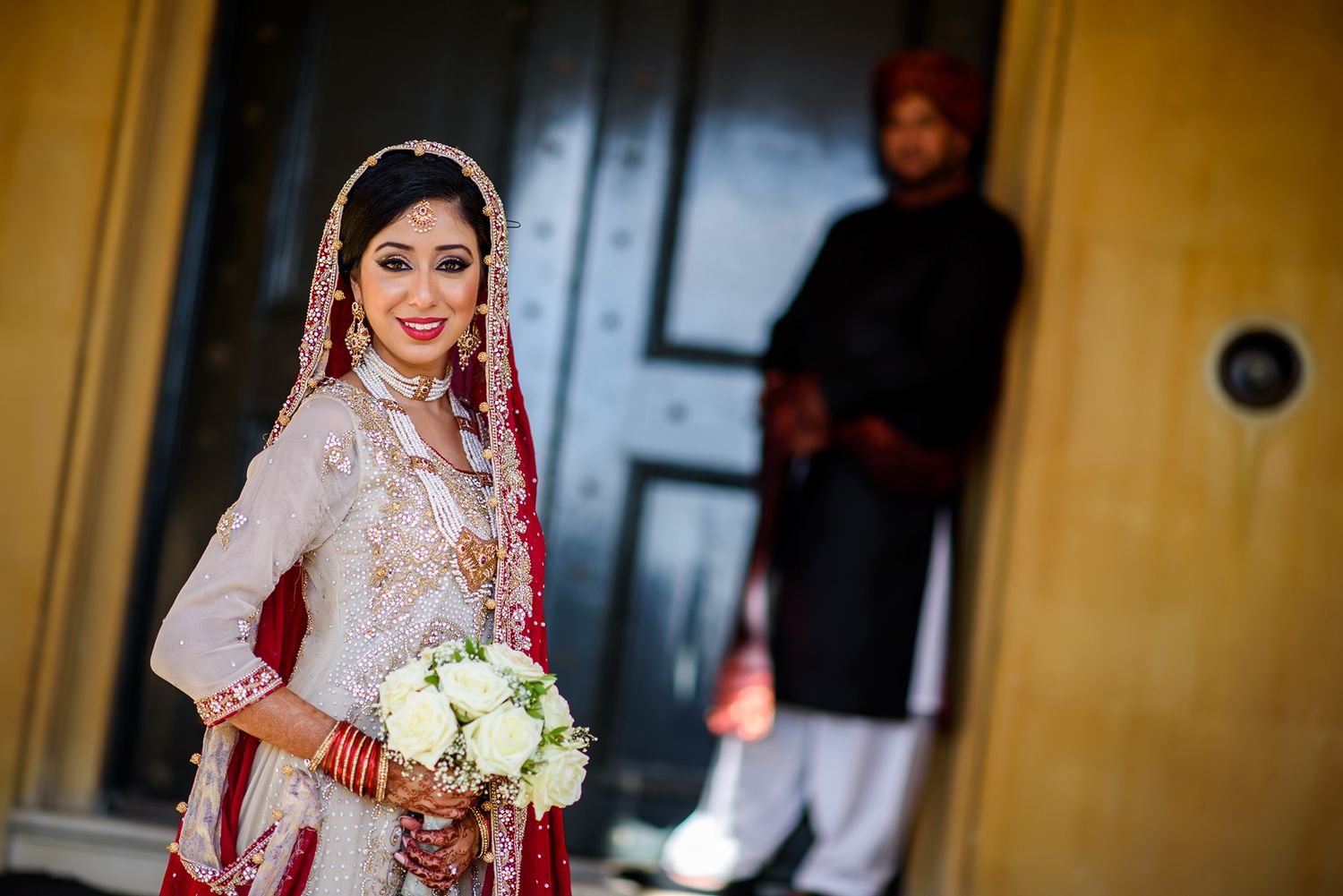 Bridal portrait with traditional South Asian wedding attire and white bouquet.