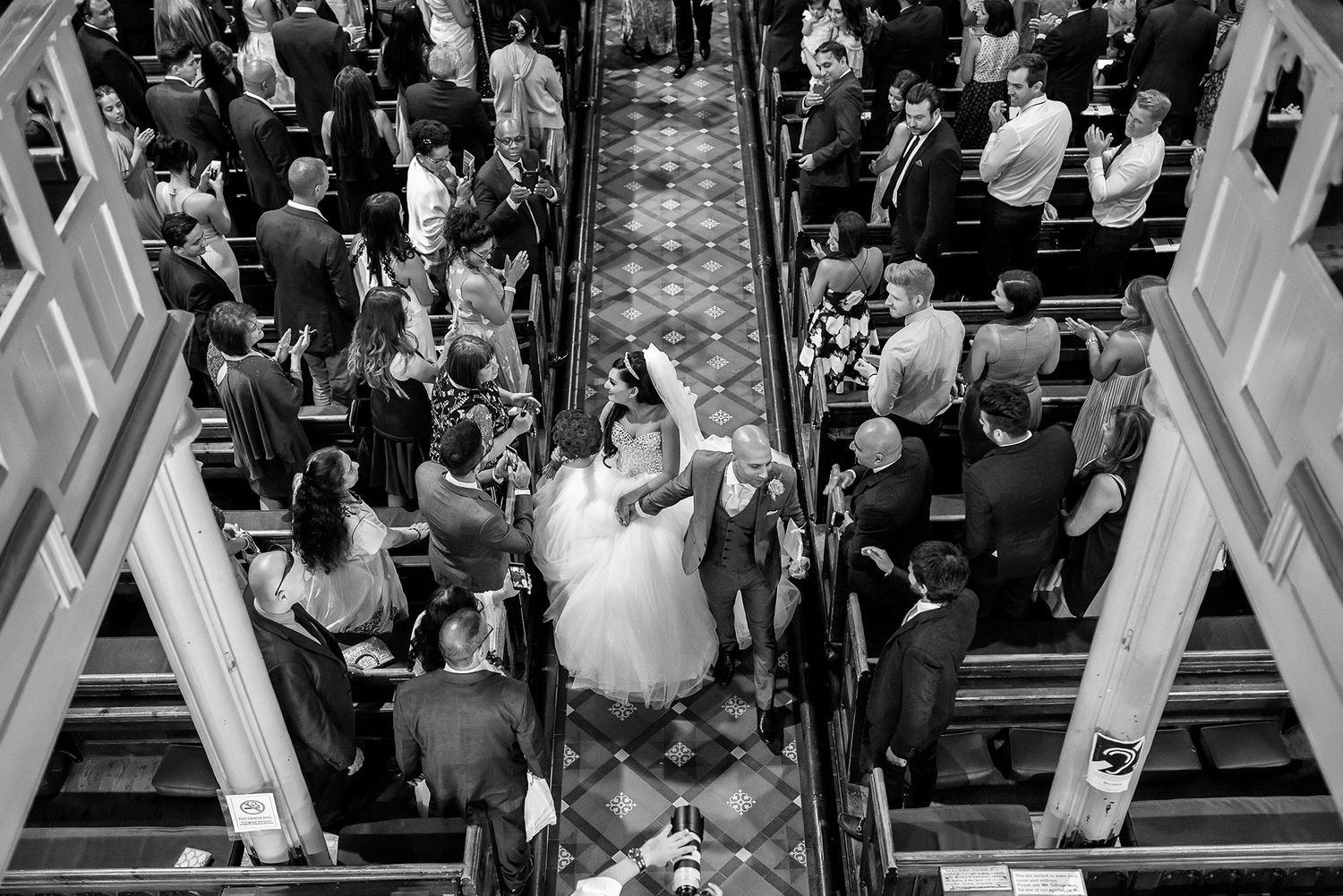 Overhead view of wedding ceremony in traditional church with decorated aisle.