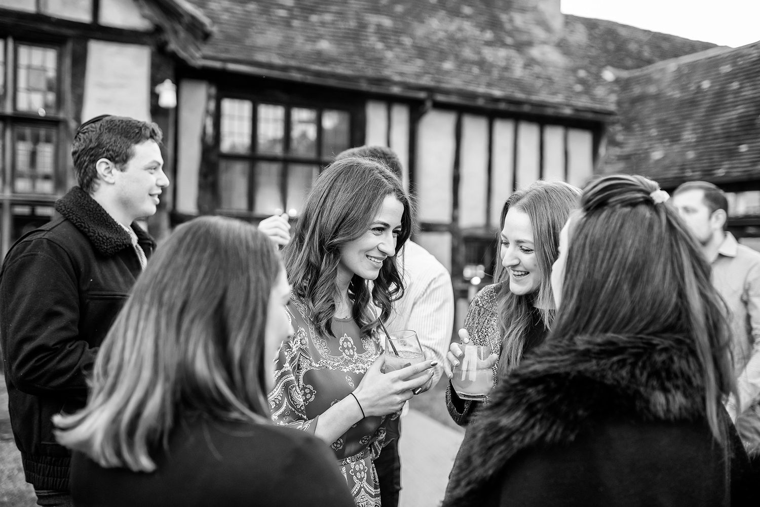 Wedding guests gather outside a traditional Tudor-style building.