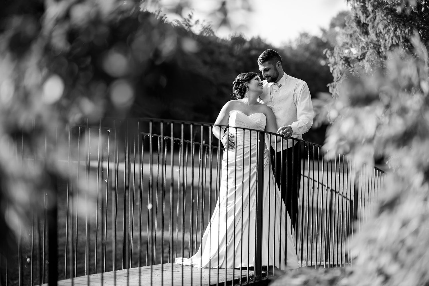 Artistic black and white wedding photography through decorative iron fence details.