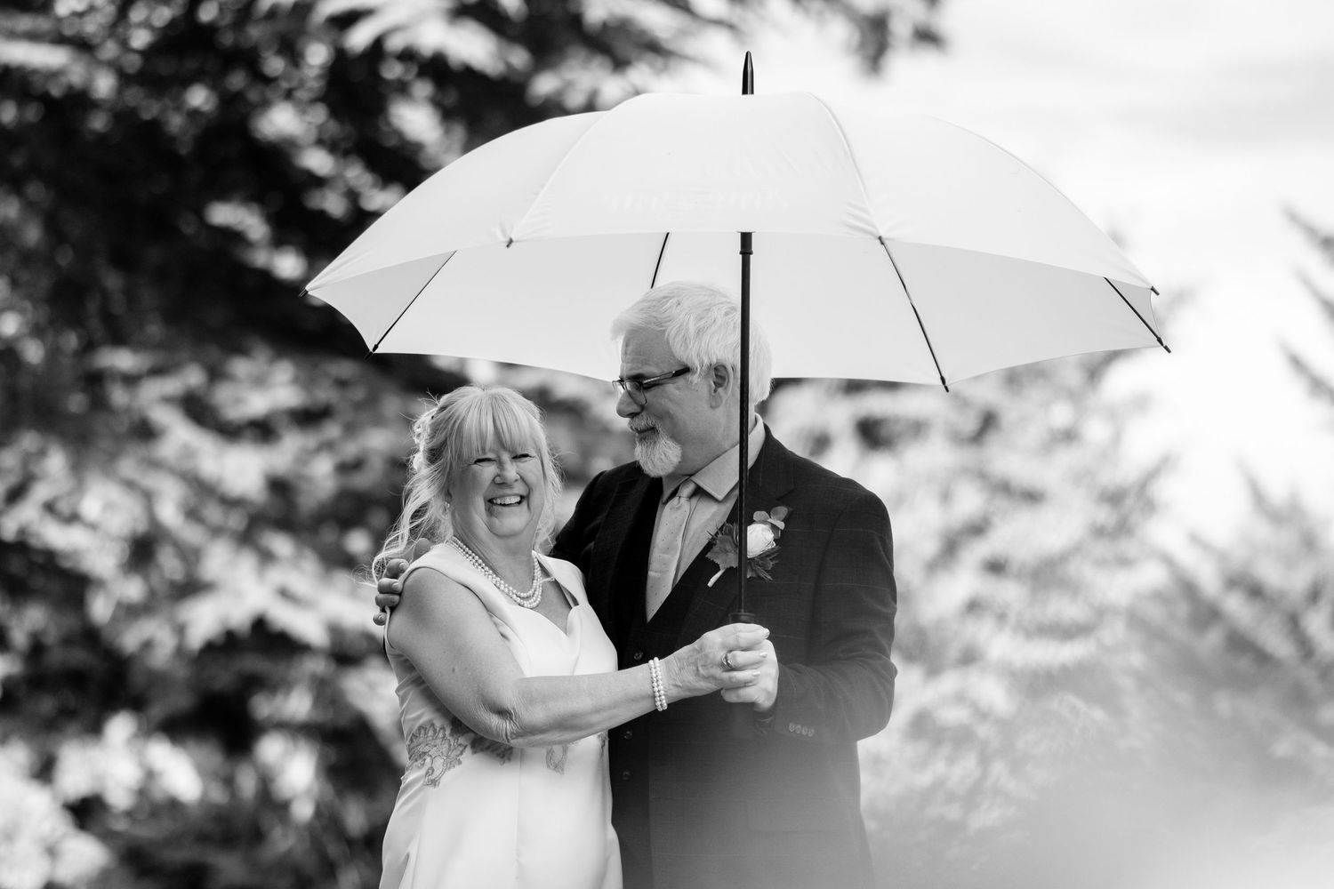 Wedding couple shares intimate moments under white umbrellas in a snowy winter setting.