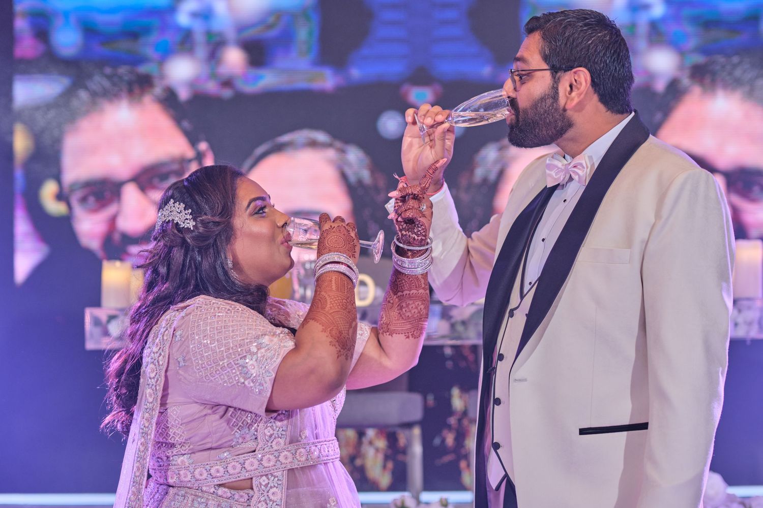 Couple sharing a dance moment at an indoor reception with purple lighting and festive atmosphere.
