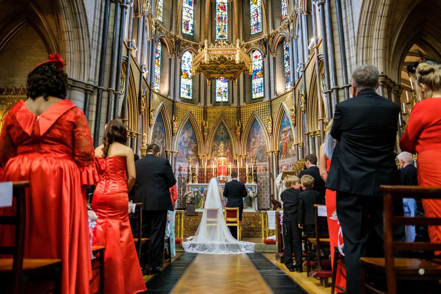 Wedding ceremony in grand cathedral with high vaulted ceilings and stained glass windows.