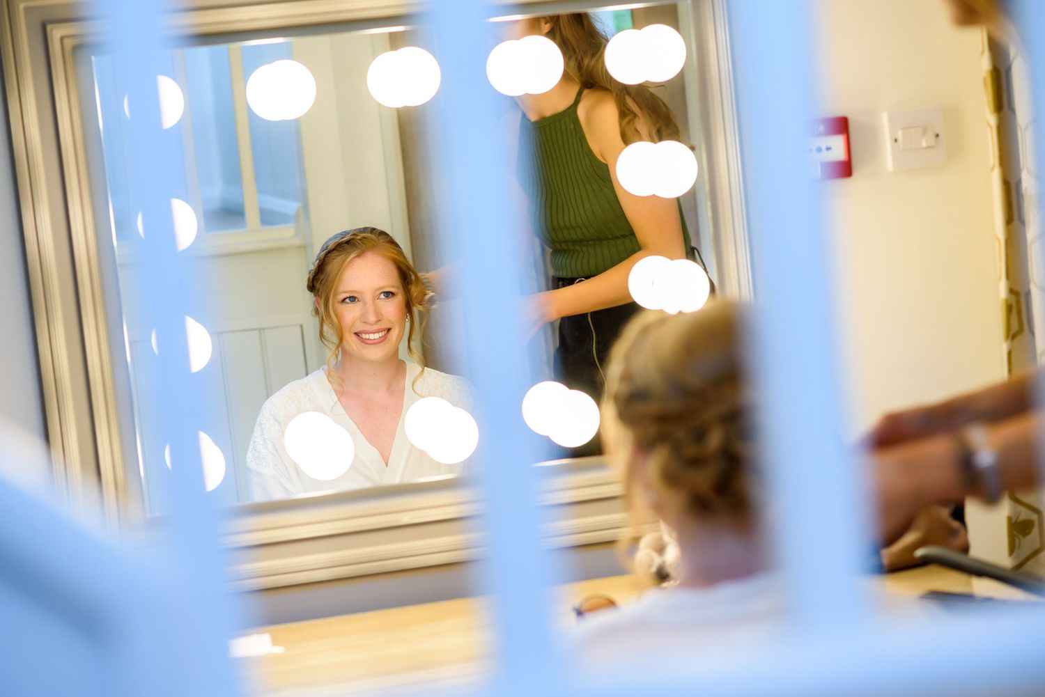 A bright dressing room mirror reflection with illuminated vanity lights glowing in a theatrical setting.