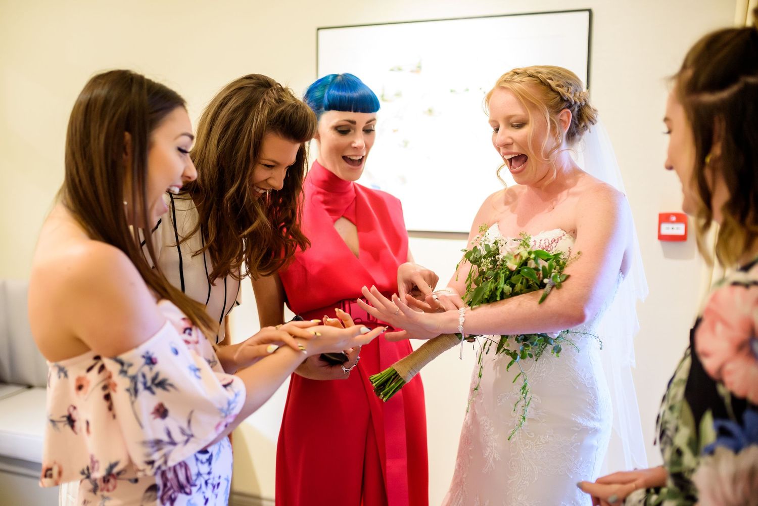 Wedding party members in red and purple dresses gather together during pre-ceremony preparations.