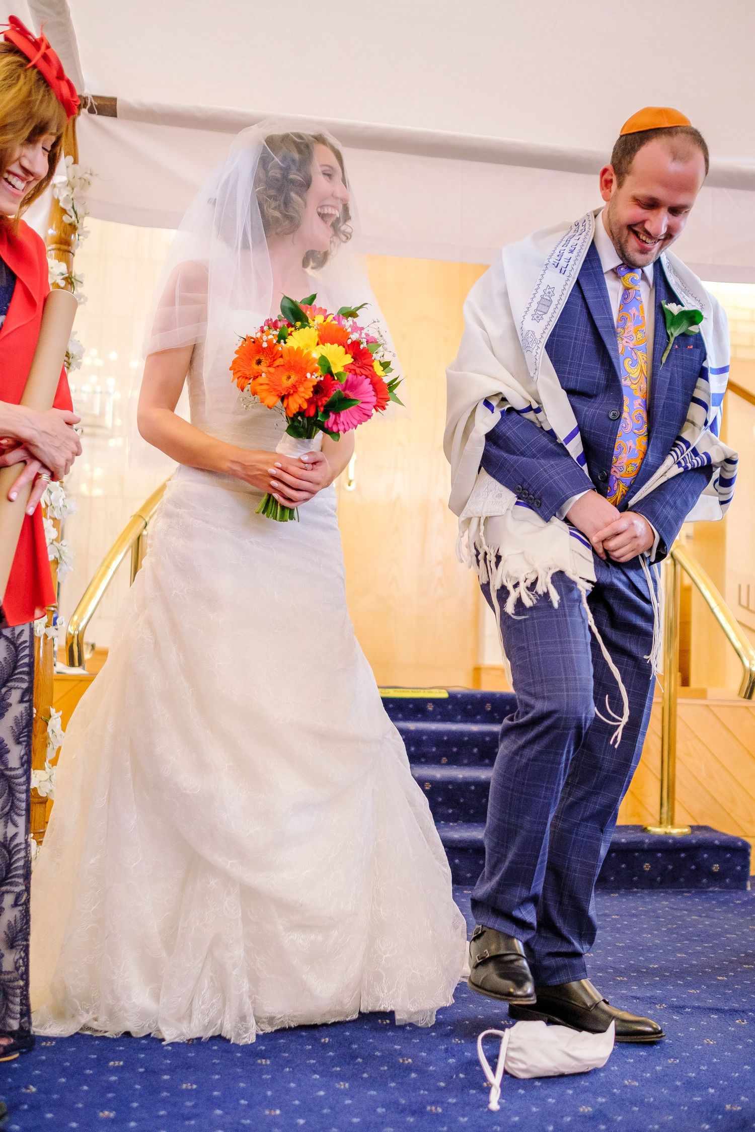 Wedding celebration on blue carpeted floor showing white dress and navy suit details.