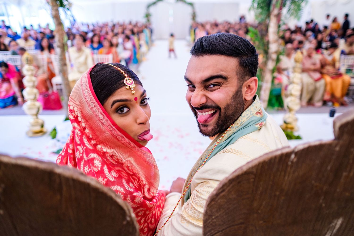 Candid moment captured during Indian wedding ceremony with bright red dupatta and cream colored attire.