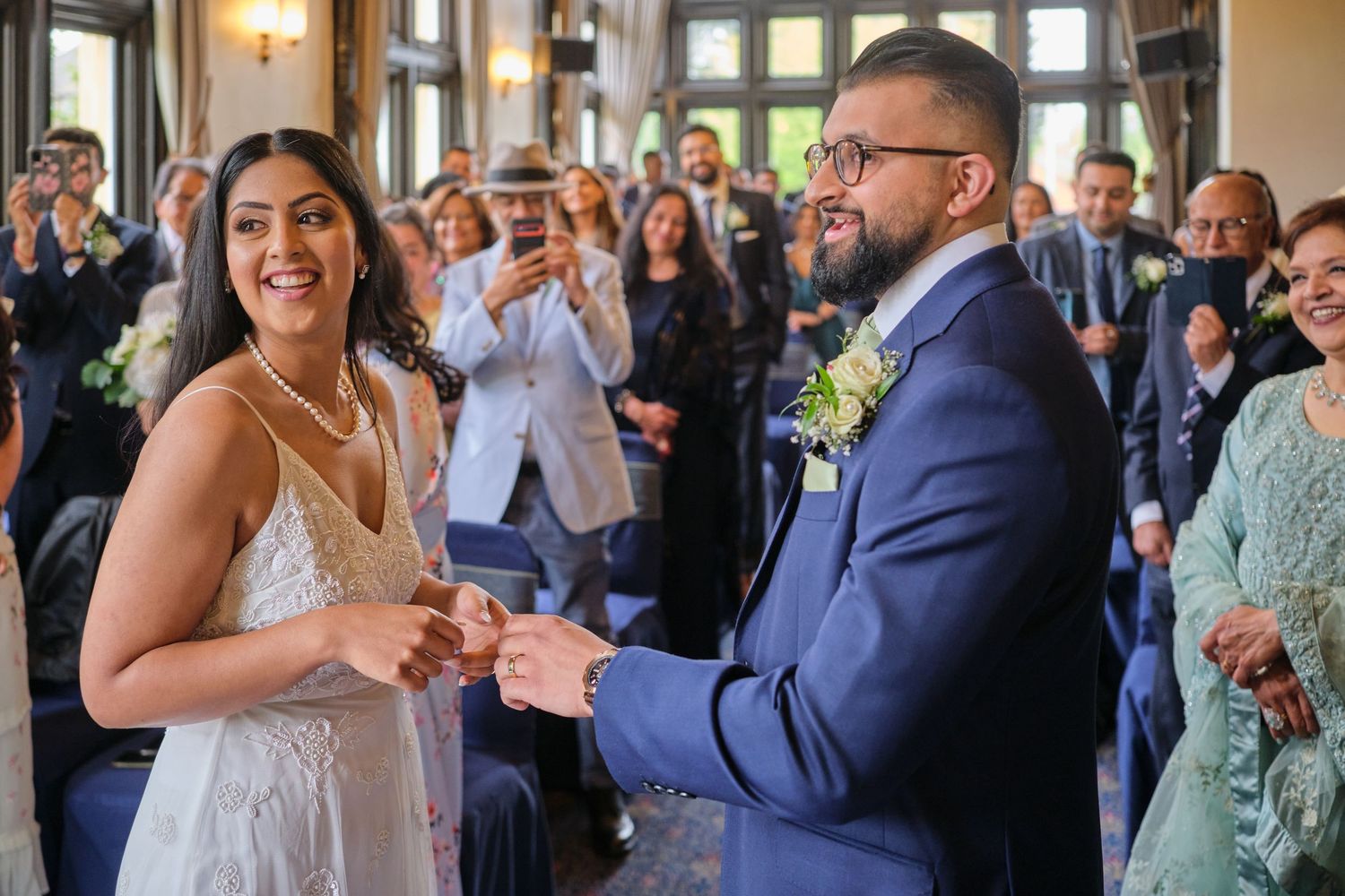 Wedding guests celebrate and applaud during a joyful reception moment at an elegant indoor venue.